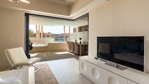 A modern living room with a TV, seating, and a view of the city.