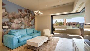 A modern living room with a blue sofa, a white coffee table, and a large floral mural on the wall.