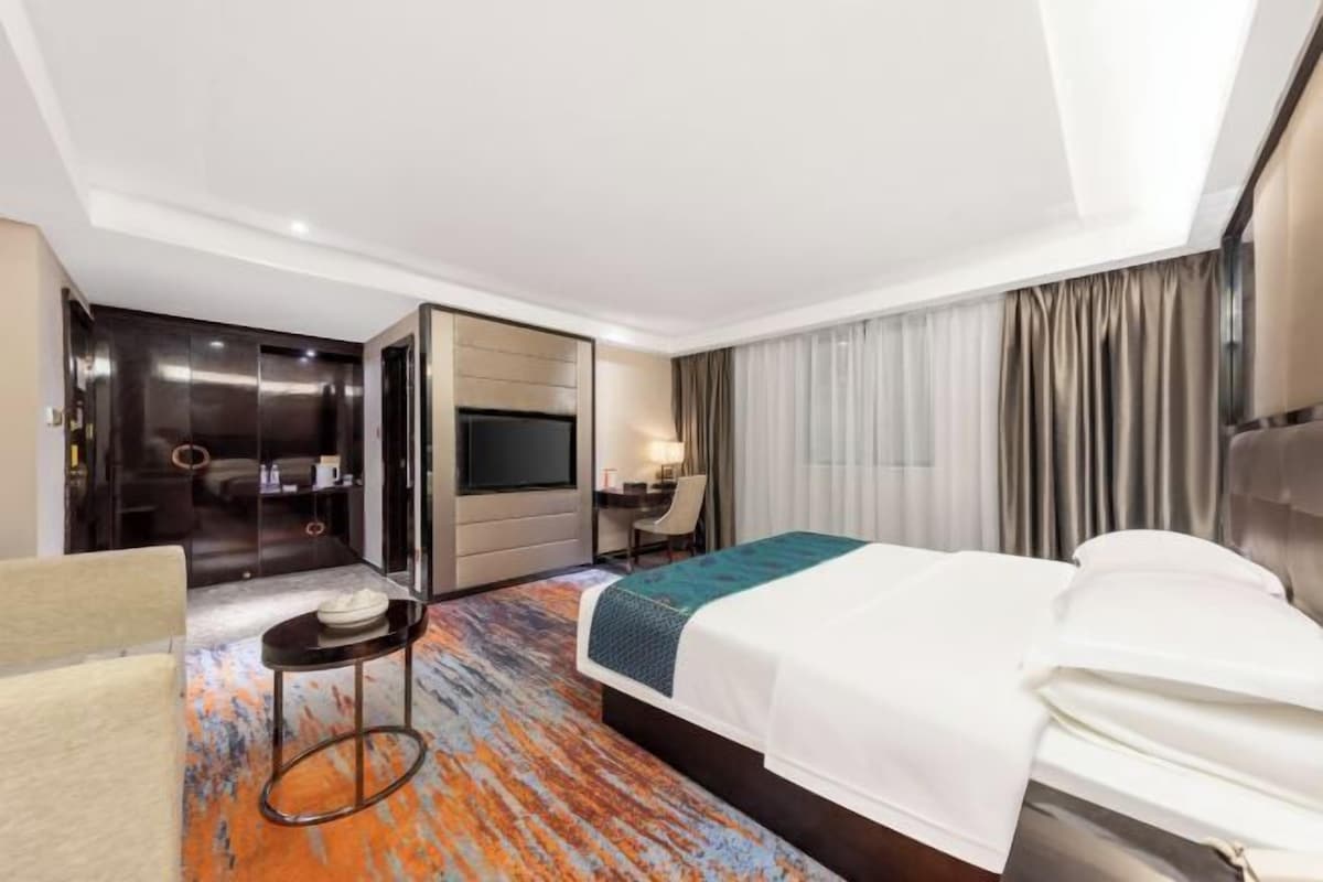 Une chambre d’hôtel équipée d’un lit, d’un bureau, d’une télévision et d’une salle de bain avec douche et toilettes.