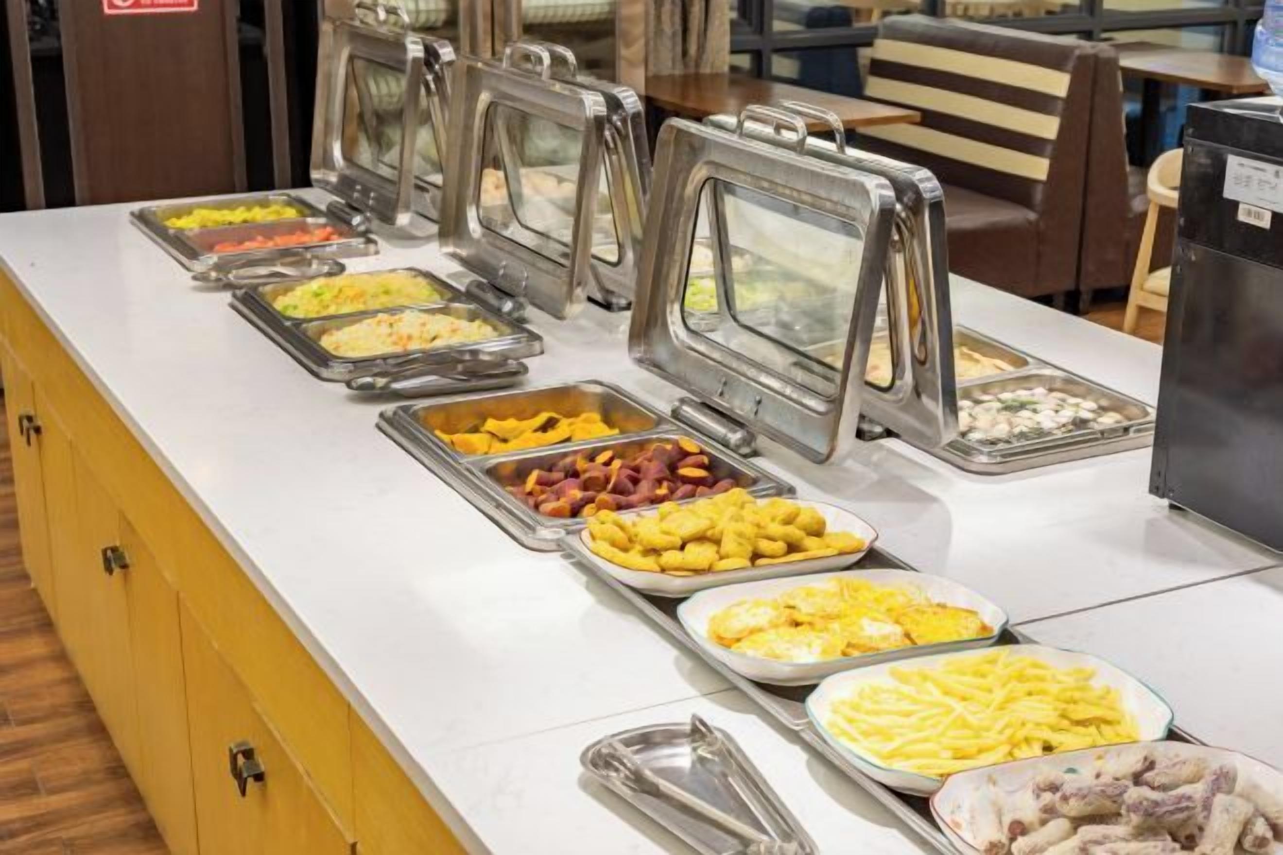 A buffet with various food options, including fruits, meats, and cheeses.