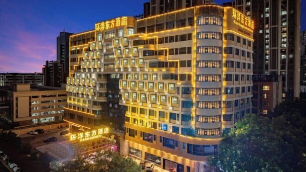 Un hotel de varios pisos con un diseño moderno, que destaca por una fachada curva e iluminación llamativa.