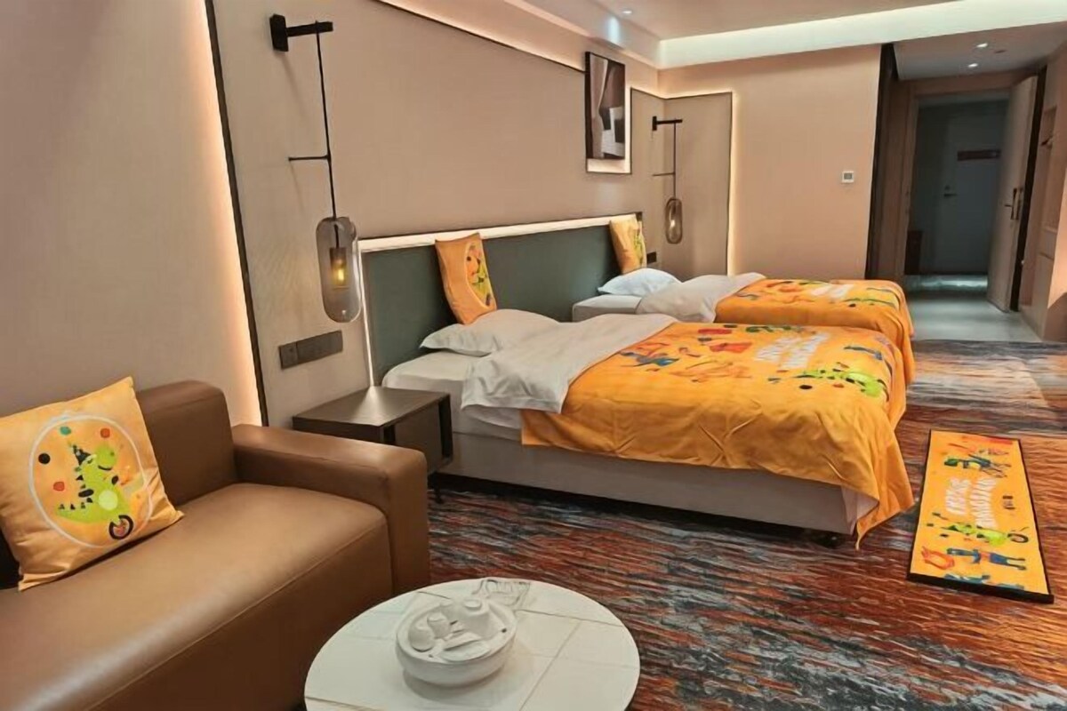 A hotel room with a bed, a sofa, a coffee table, and a carpeted floor.