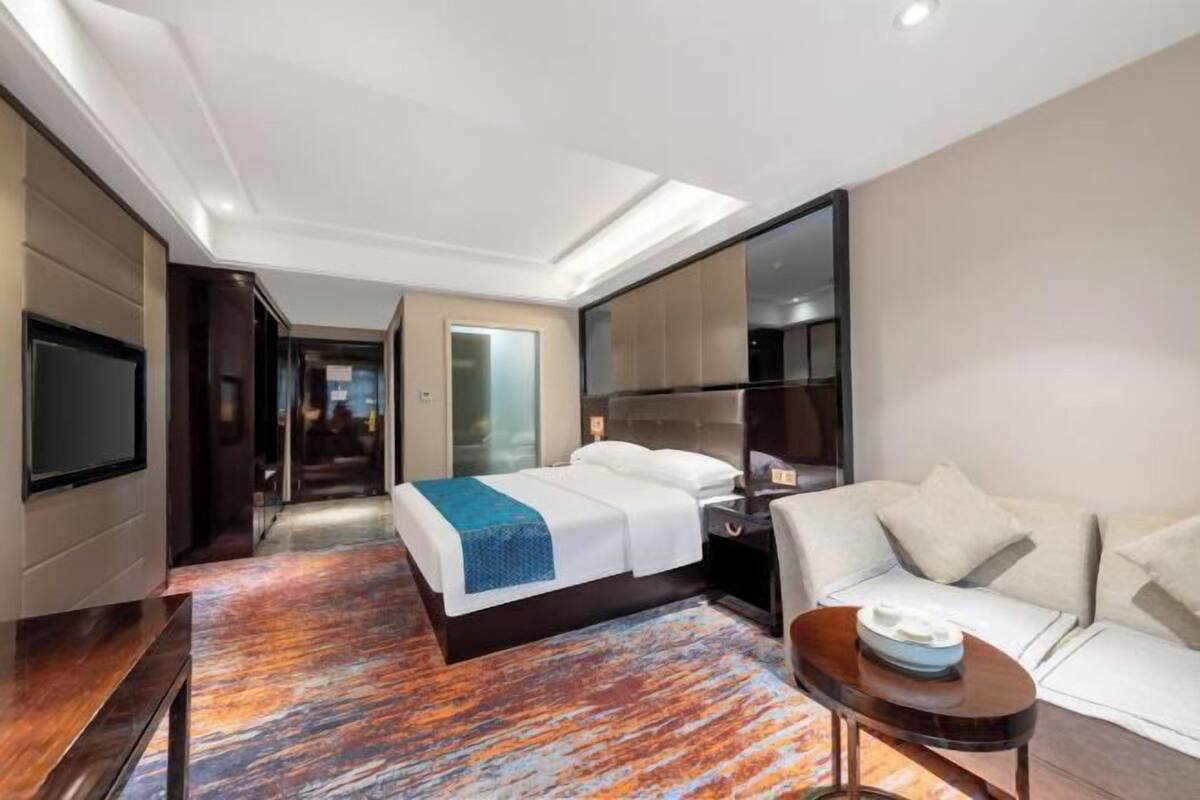 A hotel room with a bed, a sofa, a TV, and a desk.