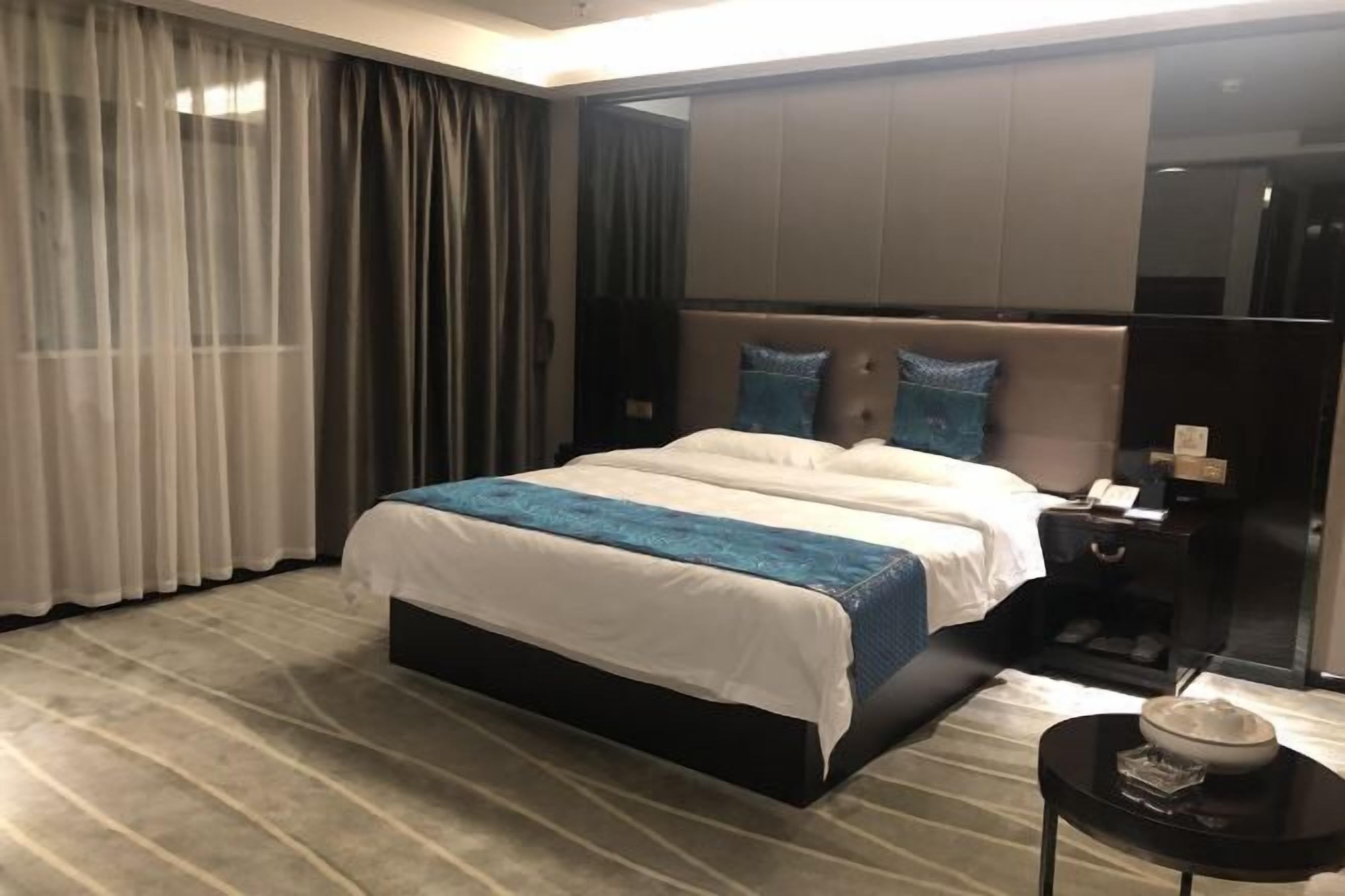 A modern hotel room with a large bed, a nightstand, and a small table with a bowl.