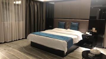 A modern hotel room with a large bed, a nightstand, and a small table with a bowl.