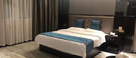 A modern hotel room with a large bed, a nightstand, and a small table with a bowl.