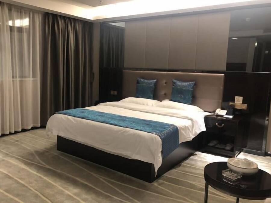 A modern hotel room with a large bed, a nightstand, and a small table with a bowl.