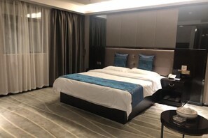 Una habitación de hotel moderna con una cama grande, una mesita de noche y una pequeña mesa con un bol.