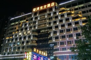 A multi-story hotel with illuminated signage and a modern architectural design. - Huanyang Oriental Hotel (Shantou)