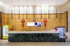 Un comptoir d’accueil doté d’un écran numérique, d  ’une télévision et d’un mur décoratif agrémenté de luminaires suspendus.