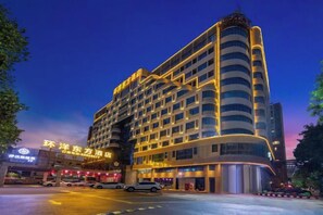 Un hotel de varios pisos con fachada curva, ventanas grandes y una entrada destacada con toldo.