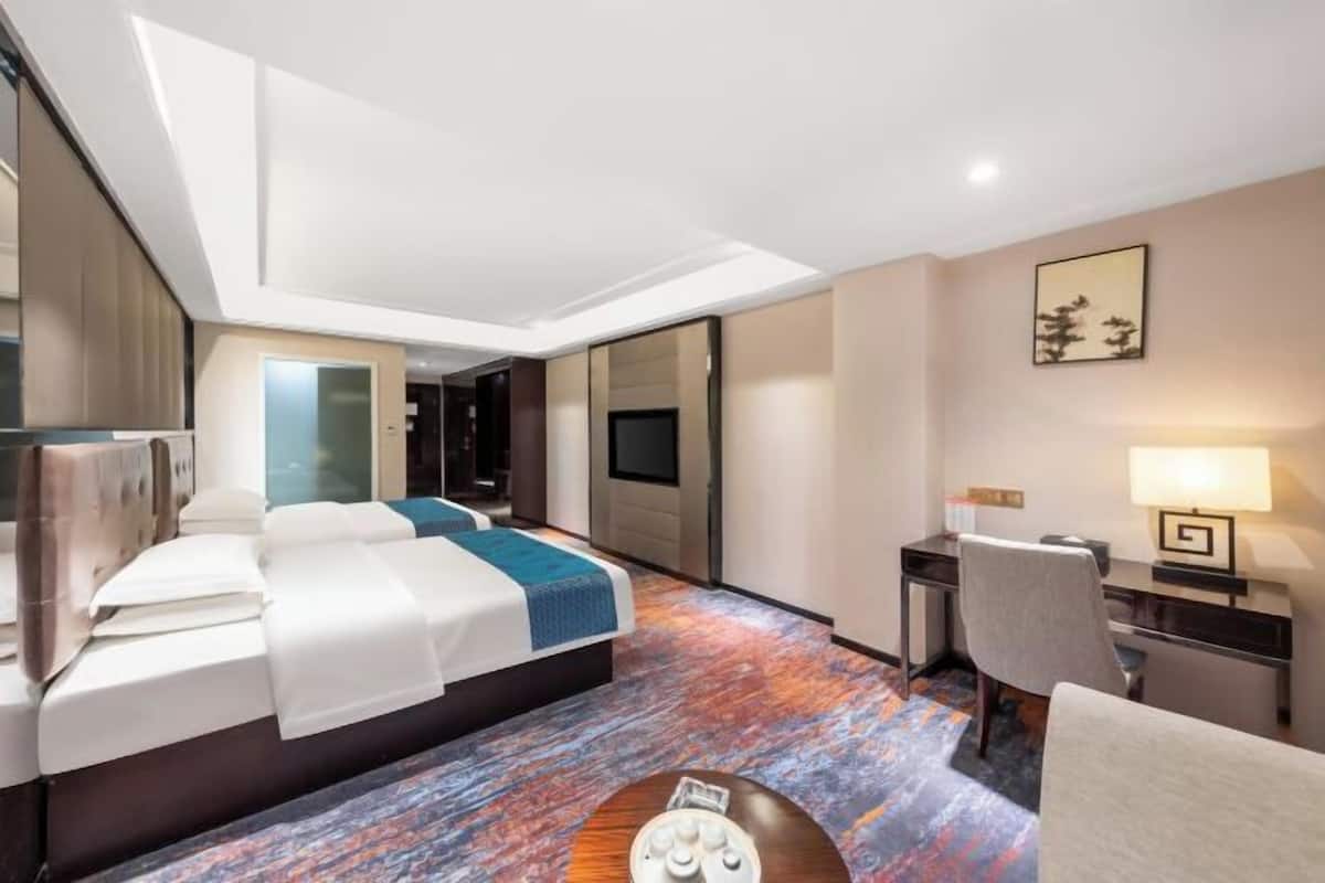 A hotel room with a bed, desk, chair, and a TV.
