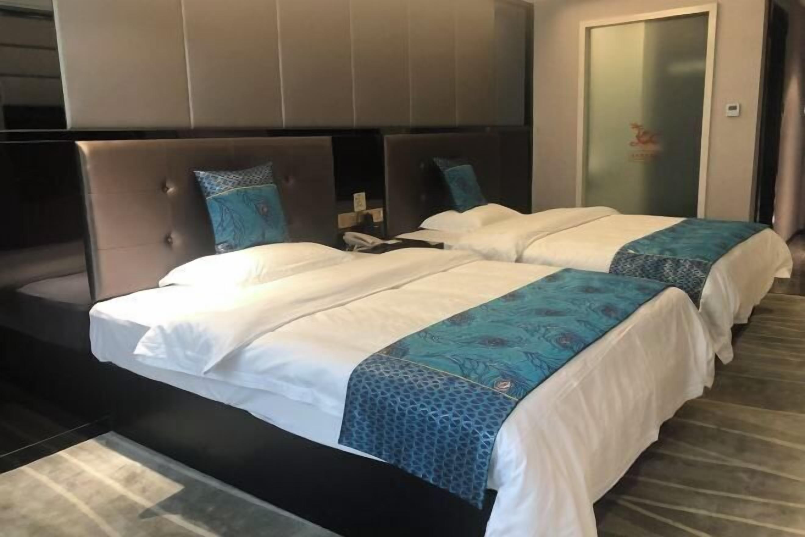 A hotel room with two beds, a large headboard, and a glass door.