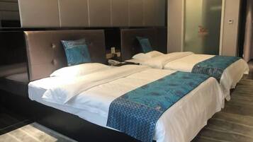 A hotel room with two beds, a large headboard, and a glass door.