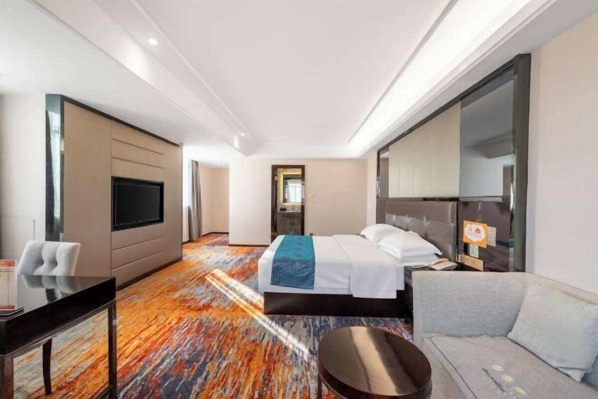 A hotel room with a bed, a sofa, a TV, and a desk.