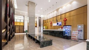 Un moderno vestíbulo de hotel con una recepción, un pilar grande y un área de estar.