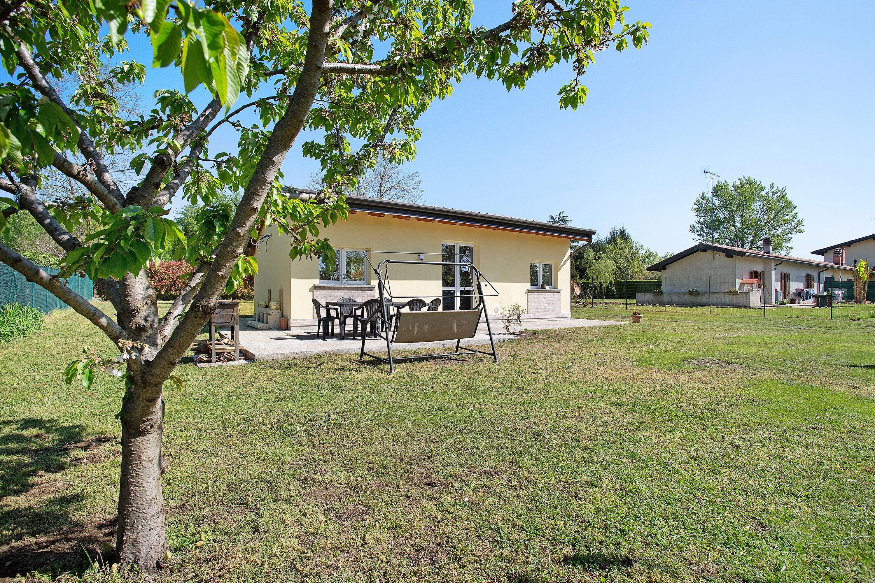 A house with a patio, a swing set, and a lawn.