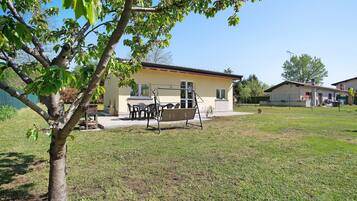 A house with a patio, a swing set, and a lawn.