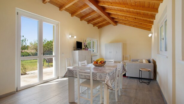 A dining area with a table, chairs, a sofa, and a television. - Holiday Home Casina Bianca with Garden, BBQ & Wi-Fi (Lurate Cacivio)