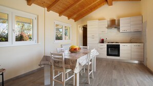 A modern kitchen with white cabinetry, a dining table with chairs, and a wooden ceiling. - Holiday Home Casina Bianca with Garden, BBQ & Wi-Fi (Lurate Cacivio)