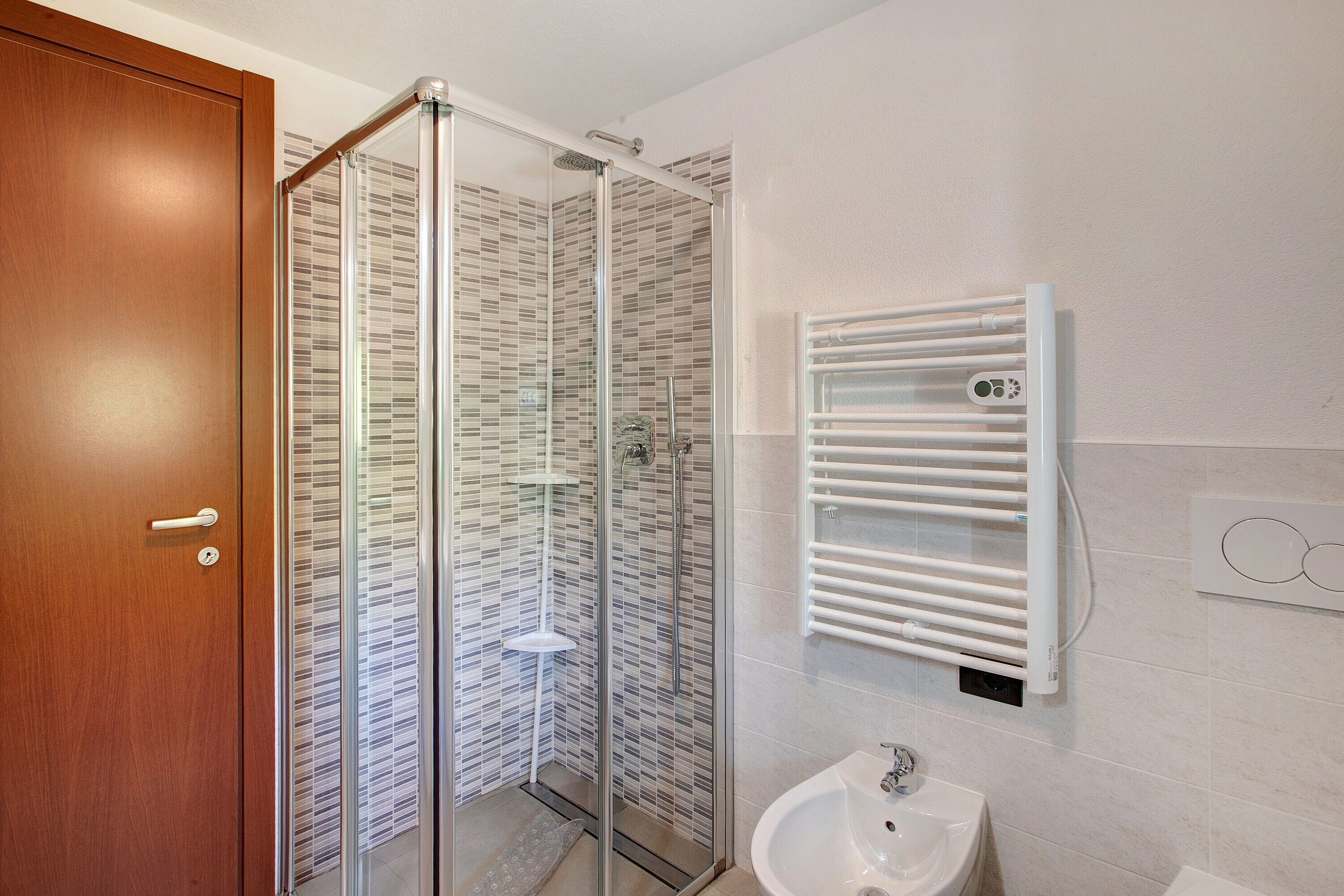 Ein Badezimmer mit Duschkabine, weißem Waschbecken und Handtuchhalter.