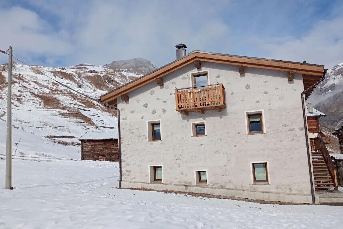 A two-story building with a balcony, multiple windows, and a mountainous backdrop.