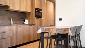 Eine moderne Küche mit Holzausbau, einem eingebauten Backofen und einem Essbereich mit Tisch und Stühlen.
