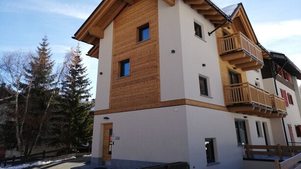 Ein mehrstöckiges Gebäude mit Holzfassade, Balkonen und blauem Himmel.