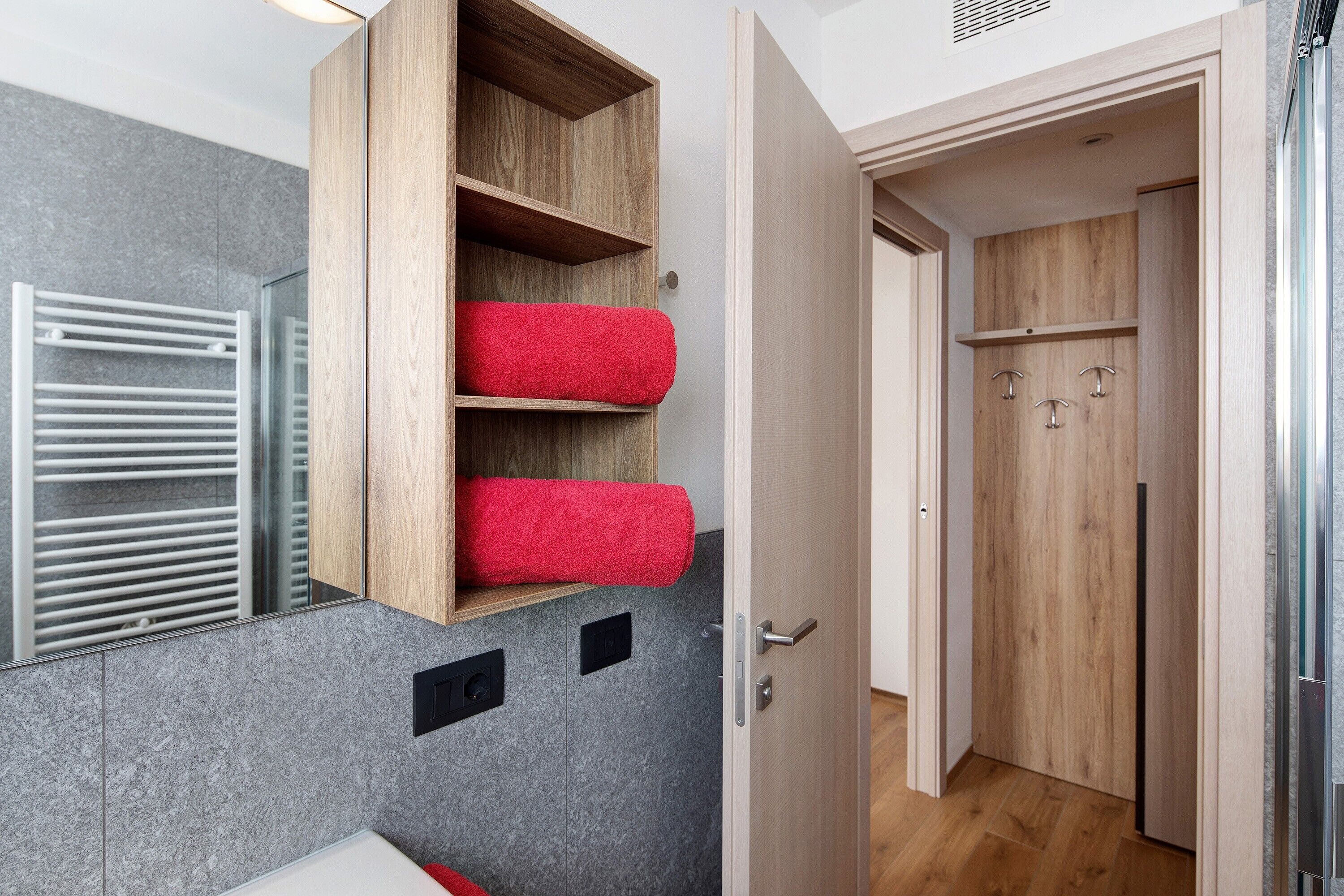 Ein Badezimmer mit einem Holzbadezimmerunterschrank, einem Handtuchwärmer und einem Spiegel.