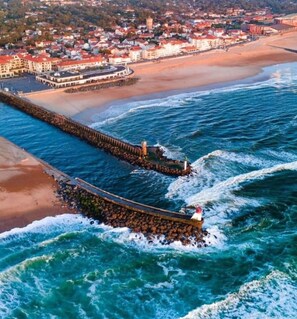 A coastal town with a long pier extending into the sea, a lighthouse at the end, and buildings along the shore. - Villa Capbreton in a quiet location Beach on foot (Capbreton)