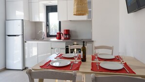 Een moderne keuken met witte kasten, een eettafel gedekt met rode placemats en een hangende rotanlamp.