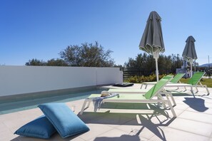 A poolside area with lounge chairs, umbrellas, and a small pool.