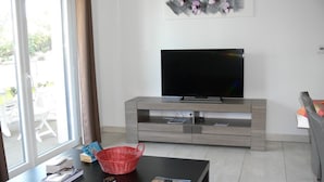 A modern living room with a flat-screen TV, a black coffee table, and a red basket.