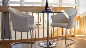 Un interior moderno con dos sillas blancas alrededor de una mesa de vidrio, una botella y un vaso.