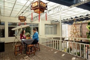 A covered outdoor area with a table and chairs, a railing, and hanging lanterns. - Domi Hotel Chain (Lijiang Ancient City Huama Street) (Lijiang)