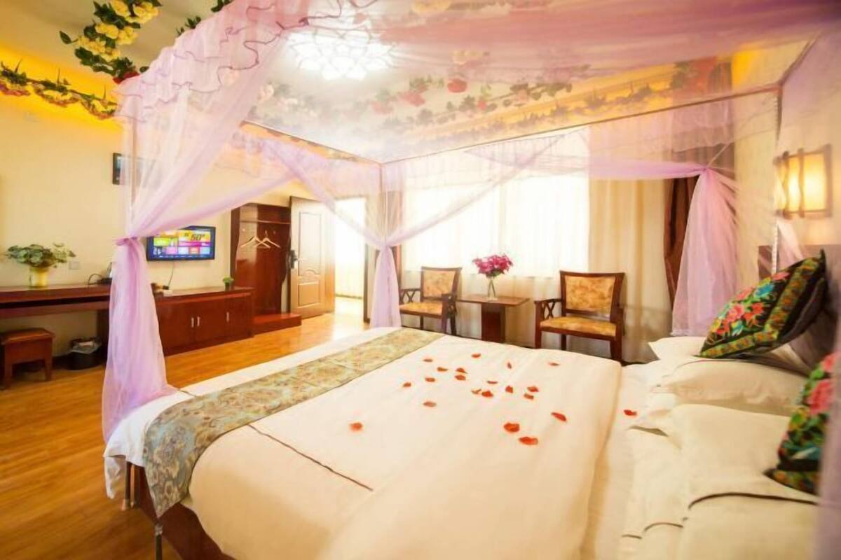Habitació d'hotel amb un llit, una taula de treball, una cadira i una televisió.