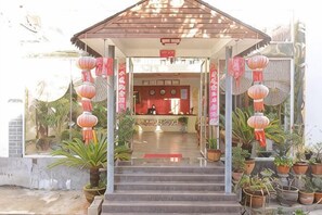 A building entrance with steps leading to a reception area, potted plants, and red lanterns. - Domi Hotel Chain (Lijiang Ancient City Huama Street) (Lijiang)
