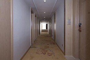 A long, narrow hotel corridor with wooden doors on both sides, a carpeted floor, and a ceiling with recessed lighting. - Vienna Hotels（hunan zhuzhou green shop） (Zhuzhou)