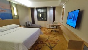 Una habitación de hotel con una cama grande, un escritorio con una silla, una televisión y una ventana con cortinas.