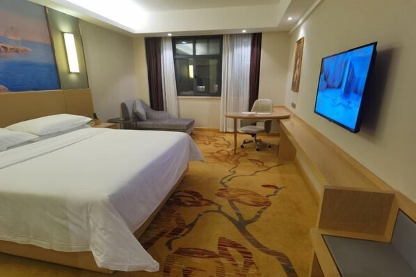 A hotel room with a large bed, a desk with a chair, a television, and a window with curtains. - Vienna Hotels（hunan zhuzhou green shop） (Zhuzhou)