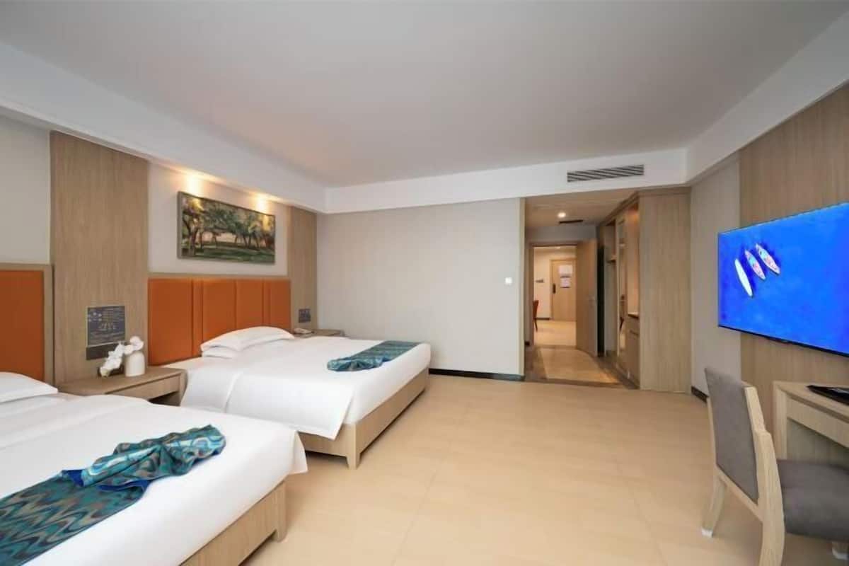 A hotel room with two beds, a flat-screen TV, and a painting on the wall.