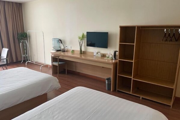 A hotel room with two beds, a desk with a computer, a TV, and a wardrobe.