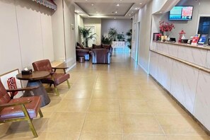 A hotel lobby with a reception desk, seating area, and a hallway leading to a dining area. - Pebble Motel (Jianhu Bus Station) (Jianhu)