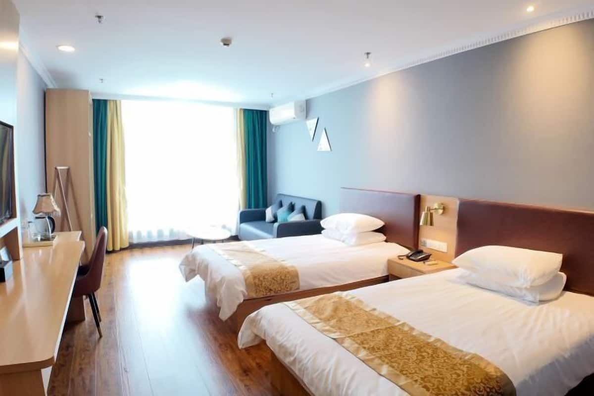Ein Hotelzimmer mit zwei Betten, einem Schreibtisch, einem Stuhl und einem Fernseher.