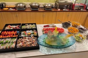 Buffet com diversos alimentos e um arranjo decorativo.