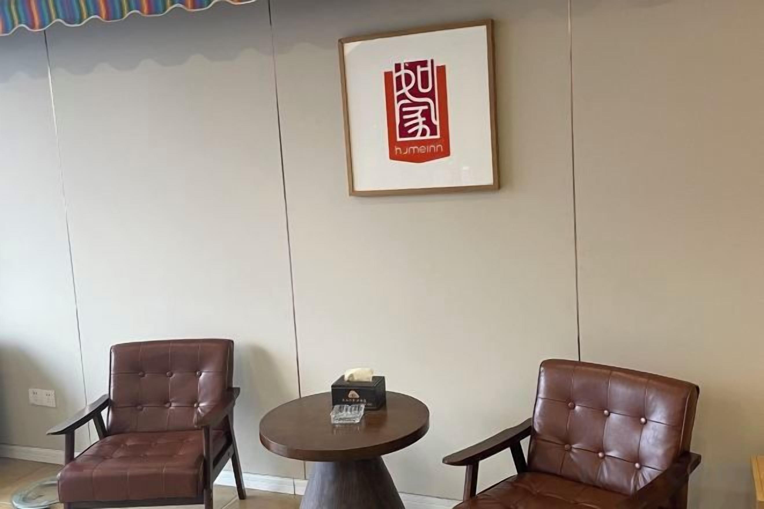 A room with two leather chairs and a small round table with a box on it.