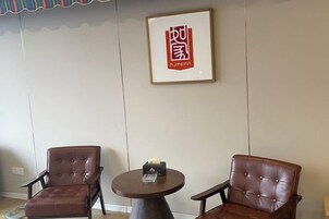 A room with two leather chairs and a small round table with a box on it.