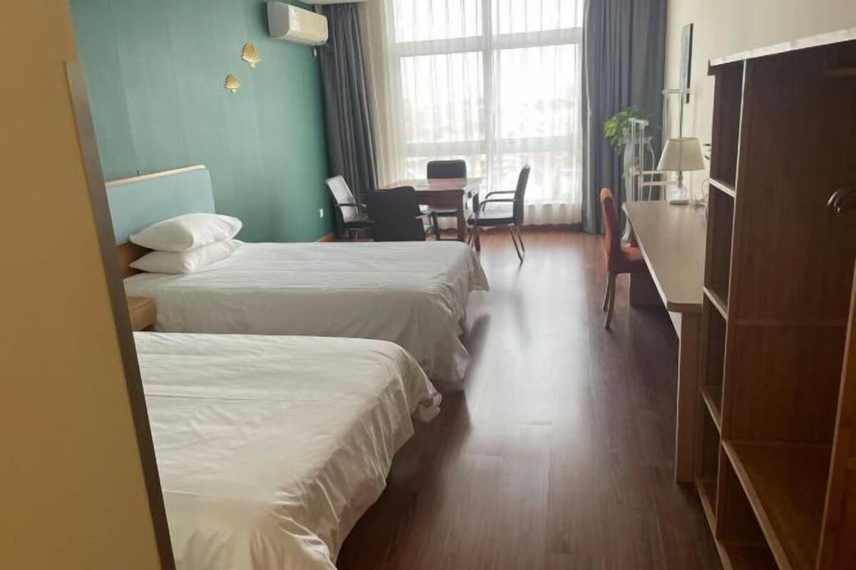 Ein Hotelzimmer mit zwei Betten, einem Schreibtisch, einem Stuhl und einem Kleiderschrank.