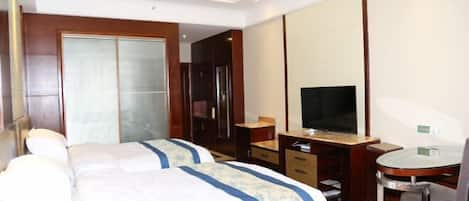 Ein Hotelzimmer mit zwei Betten, einem Schreibtisch mit Stuhl, einem Fernseher und einem großen Spiegel.
