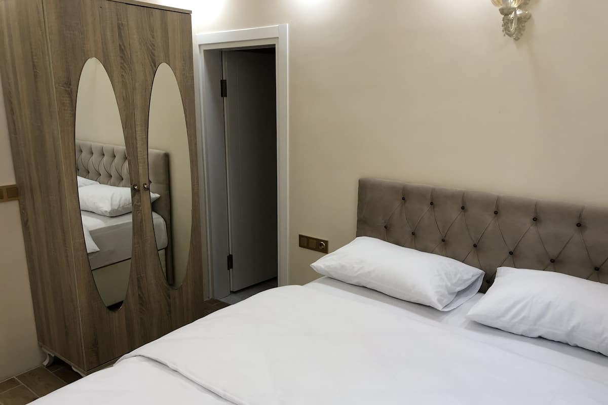 A bedroom with a bed, a wardrobe with a mirror, and a door.